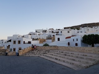 Old stone stairs with white houses of small settlement against cloudless blue sky.