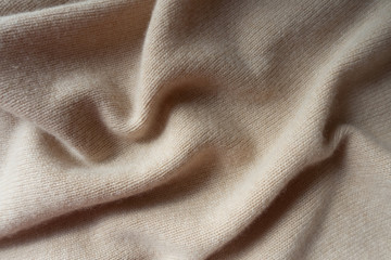 Soft folds of simple beige knitted fabric