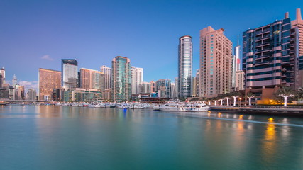 View of Dubai Marina Towers reflected in water of canal in Dubai day to night timelapse