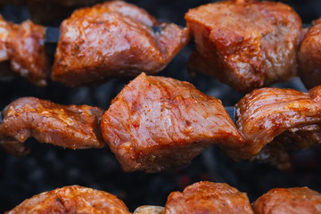 pork meat is cooked on skewers on barbecue grill close-up