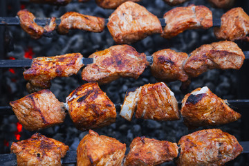 pork meat is cooked on skewers on barbecue grill close-up
