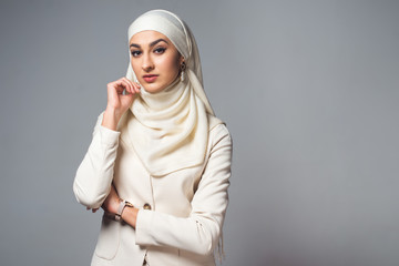 portrait of beautiful young muslim woman looking at camera isolated on grey