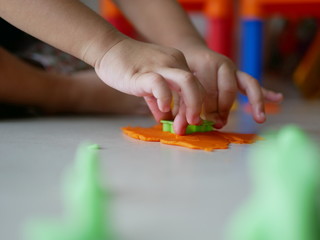 Little baby's hands applying plastic dough press on the playdough