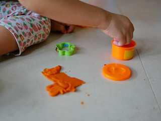 Little baby's hands collecting and putting playdough back into the box, after finish playing