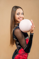 Rhythmic gymnastics school and energy. Flexibility in acrobatics and fitness health. Sport and success. Woman gymnast  with pink ball. Workout of girl on camel color background