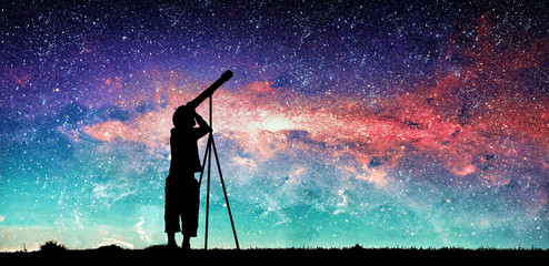 Silhouette of little child looking through a telescope