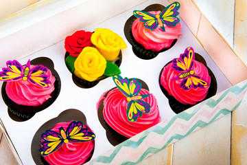 Selection of handmade cupcakes with a floral and butterfly design in different colours
