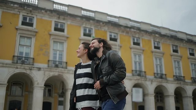 Slow motion shot of young smiling couple hugging and strolling on street of old city.