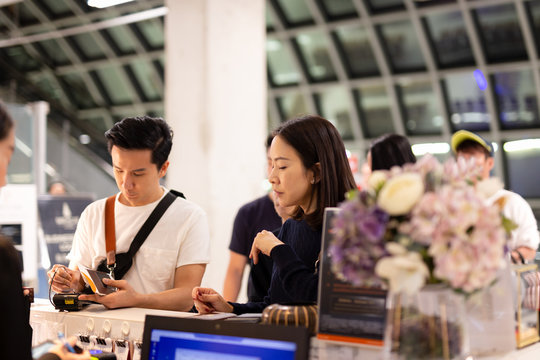 Asian Couple Signing Bill For Hotel Room At Reception.