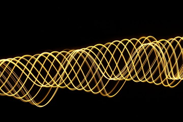 Light painting, long exposure photography, vibrant metallic gold color and motion against a black...