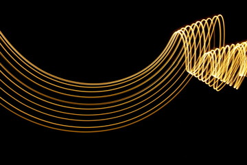 Light painting, long exposure photography, metallic gold color against a black background