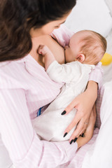 young mother breastfeeding little baby at home