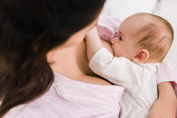 partial view of mother breastfeeding little baby at home