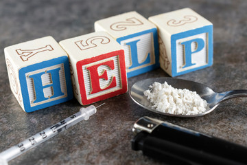 Help spelled out in blocks with a syringe and spoon with white powder (wheat flour depicting...