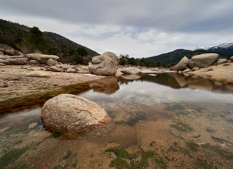 reflections in the burguillo reservoir with the snowy mountains in the background