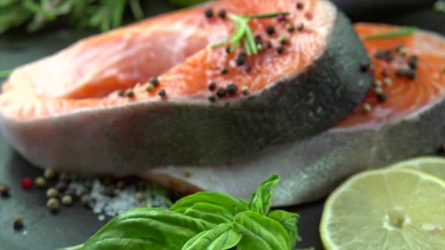Salmon. Raw trout fish steak with herbs and lemon on slate. Cooking, seafood. Healthy eating concept. Slow motion 4K UHD video 3840x2160