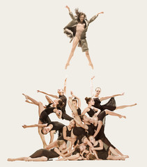 The group of modern ballet dancers dancing on gray studio background