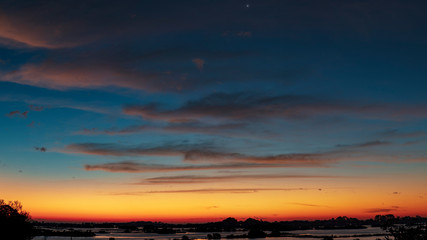 Dramatic blue, orange, red and yellows fill the winter morning sky over a Gulf of Mexico bayou in Florida's Nature Coast community