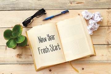 new year, fresh start on notebook on wooden table