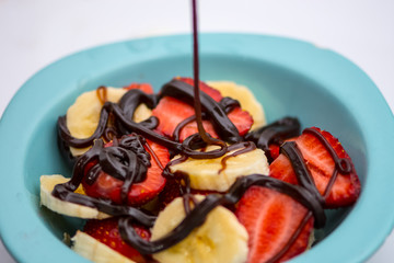 The chocolate pouring on the prepared fruit salat
