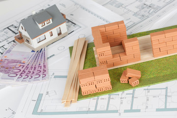 Model house construction with brick on blueprint and five hundred euro banknote
