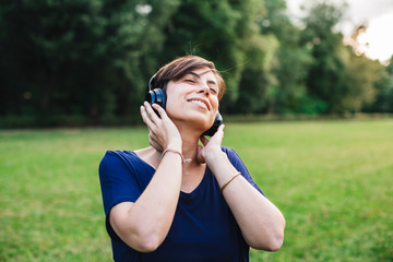 Young adult woman listening music at park