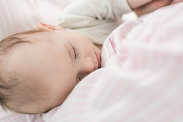 Fototapeta na wymiar partial view of cute baby sleeping on mothers hands