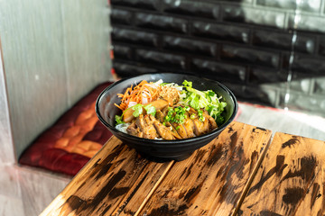 Delicious Thai inspired noodle bowl with chicken, carrots, scallions, and lettuce. Food from Thailand.