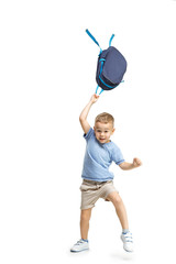 Full length portrait of cute little kid boy in stylish clothes jumping with bag against white studio wall. Kids fashion concept