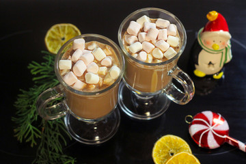two glass mugs with hot cocoa and marshmallow in the new year decor.