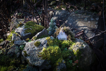 Christmas and New Year miniature house at forest in the sunlight. Little toy house close up. Festive background. Christmas decorations. Holiday and celebration concept.