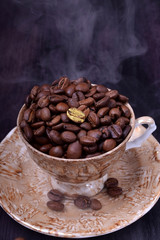 Golden coffee bean on freshly roasted ones in a cup against the dark background