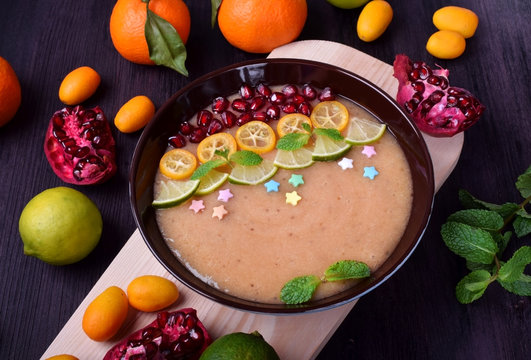 Smoothie bowl garnished with kumquats, pomegranate, lime, mint and sugar sprinkles
