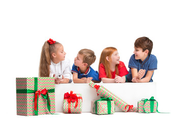 Full length portrait of cute little kids girls and boys in stylish clothes looking at camera and smiling against white studio wall with gifts. Kids fashion concept