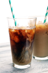 Ice coffee on a rustic table with cream being poured into it showing the texture and refreshing look of the drink