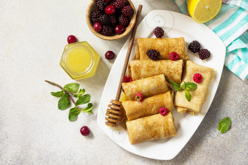 Healthy Pancakes breakfast. Stack of homemade thin pancakes or crepes whole grain flour, served with honey and fresh berries. Top view flat lay background.