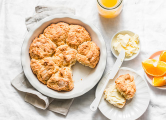 Served breakfast table - fresh pastries, butter, orange juice on a light background, top view