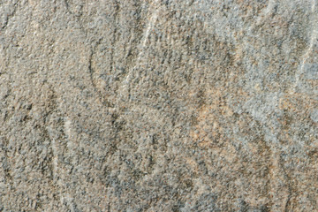 The texture of a light gray stone with beige patches and a rough and matte surface. Grunge background with space for text or image. Gray backdrop.