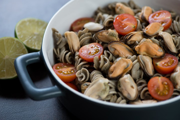 Close-up of fusilli made of hemp flour and served with tomatoes and mussels in a bowl, studio shot