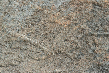 The texture of a light gray stone with beige patches and a rough and matte surface. Grunge background with space for text or image. Gray backdrop.