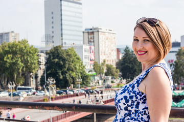 Beautiful Girl in a Blue Dress Smiling and Posing With Panoramic View of the City Center Behind Her