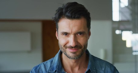 Portrait of a smiling handsome middle aged man in living room in slow motion. Shot with RED camera in 8K. Concept of lifestyle, achievement, father