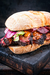 Traditional barbecue pulled pork piece of Bosten butt as sandwich with lettuce as closeup on a...
