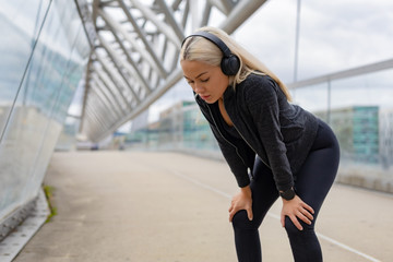 Obraz premium Tired Female Runner Resting With Hands On Knees After Workout