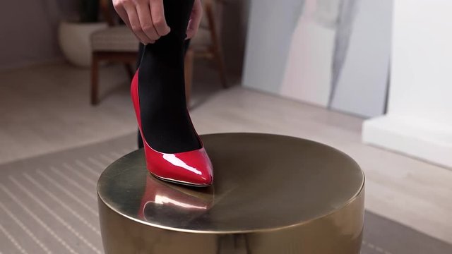 Woman in red shoes runs her hand over her leg in black stockings, women's hosiery, women's clothing and accessories, everyday looking