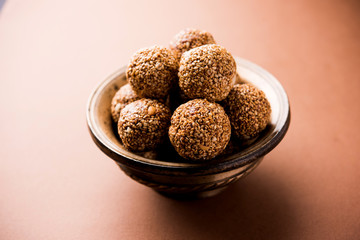 Tilgul Laddu or Til Gul balls for makar sankranti, it's a healthy food made using sesame, crushed peanuts and jaggery. served in a bowl. selective focus showing details.