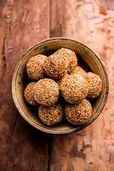 Tilgul Laddu or Til Gul balls for makar sankranti, it's a healthy food made using sesame, crushed peanuts and jaggery. served in a bowl. selective focus showing details.
