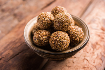 Tilgul Laddu or Til Gul balls for makar sankranti, it's a healthy food made using sesame, crushed peanuts and jaggery. served in a bowl. selective focus showing details.