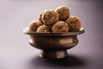 Tilgul Laddu or Til Gul balls for makar sankranti, it's a healthy food made using sesame, crushed peanuts and jaggery. served in a bowl. selective focus showing details.