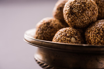 Tilgul Laddu or Til Gul balls for makar sankranti, it's a healthy food made using sesame, crushed peanuts and jaggery. served in a bowl. selective focus showing details.